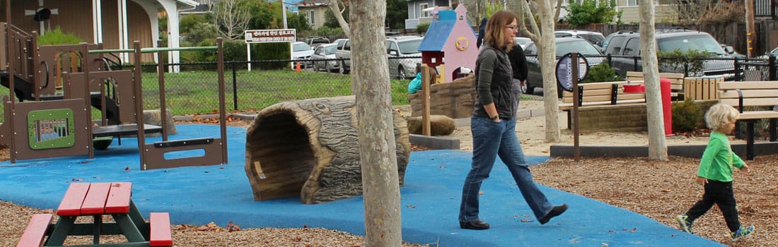 Woman and boy walking around a playground.