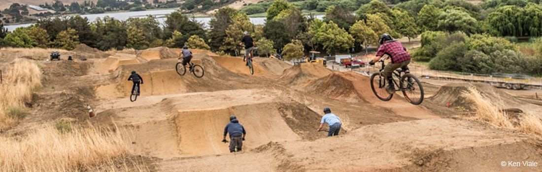 Mountain bikers riding down a bike park.